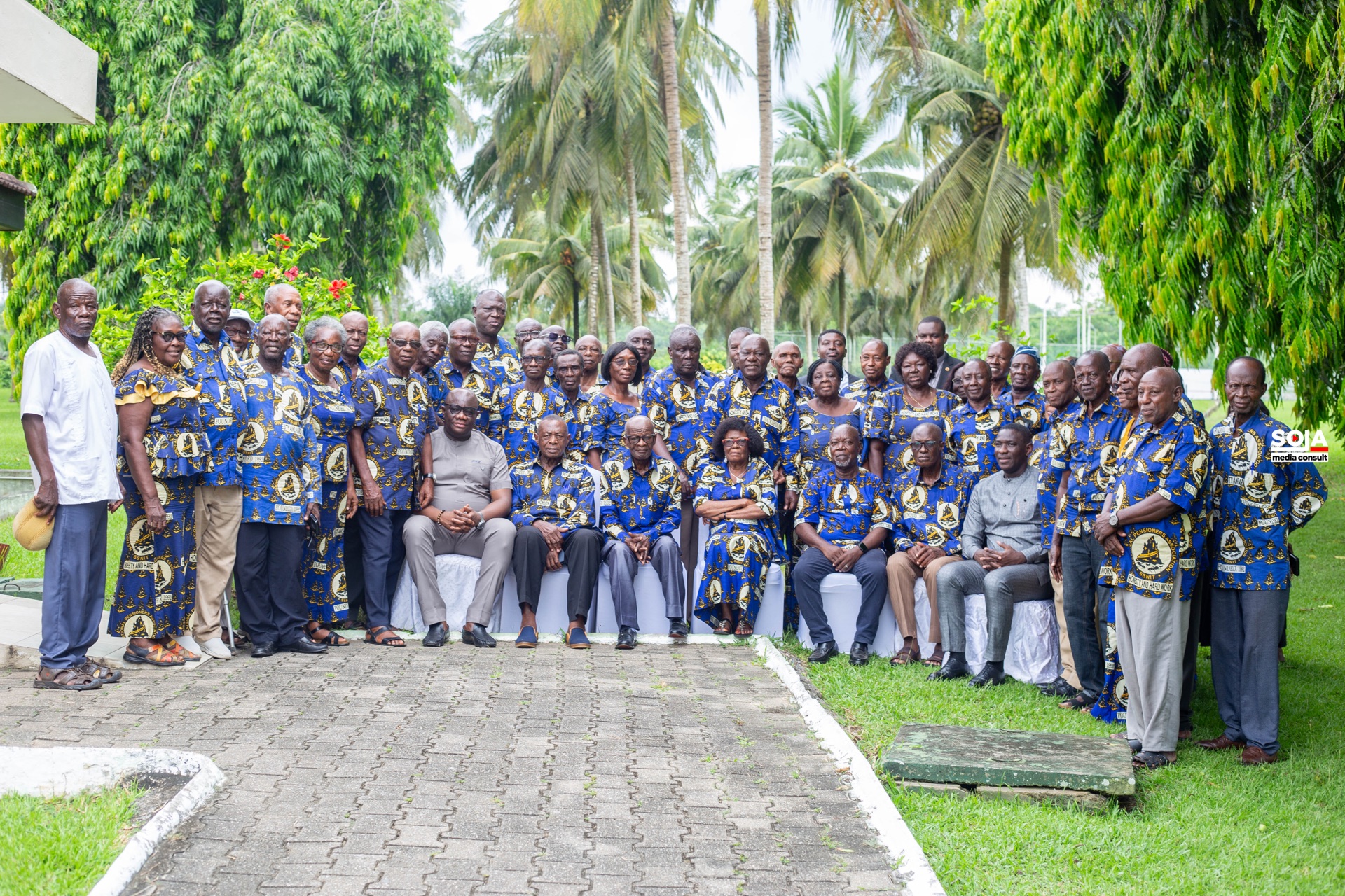 A large group of Association members gathered outdoors among palm trees